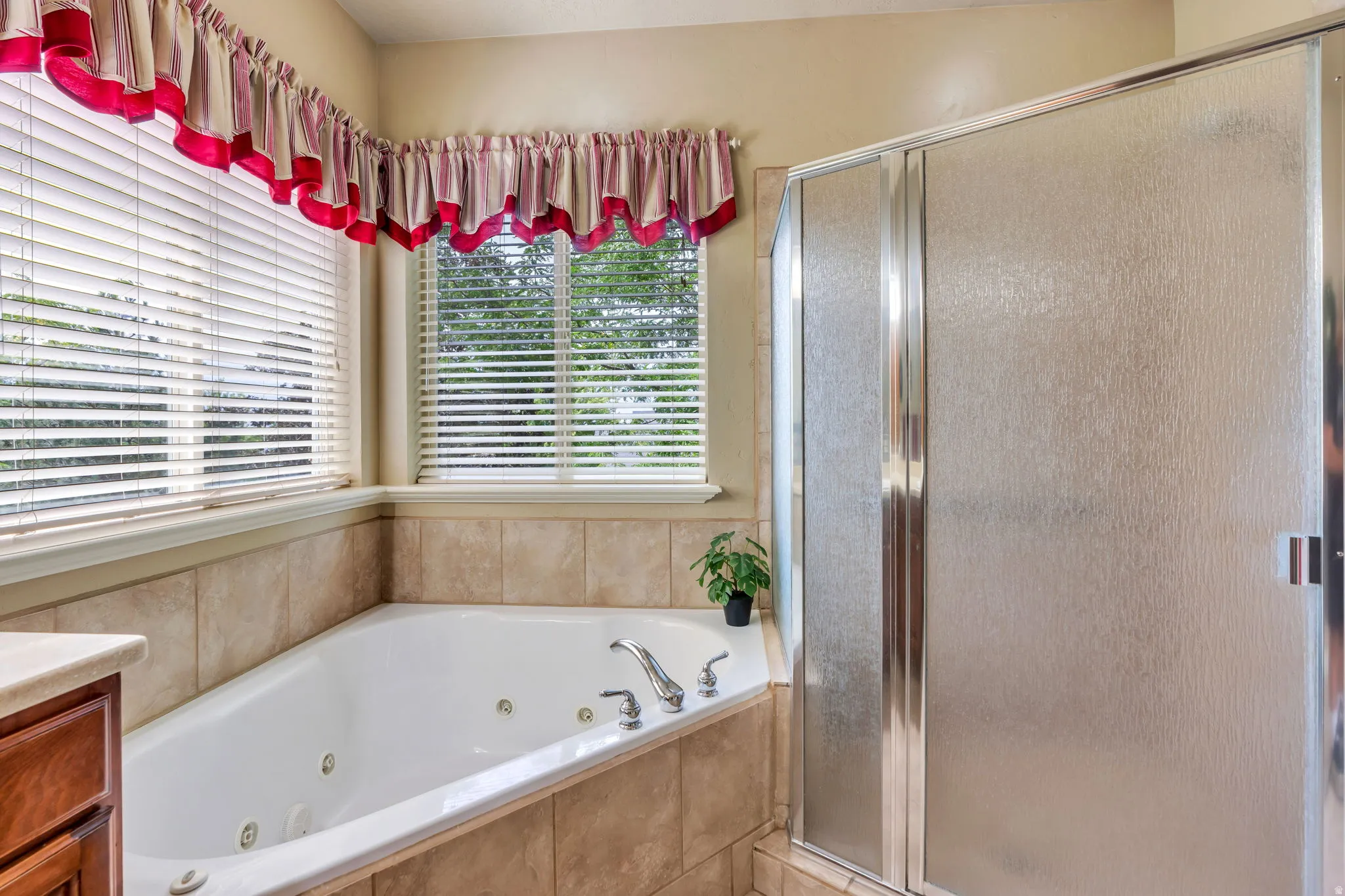 Jetted soaking tub with tile surround, framed by two windows with horizontal blinds