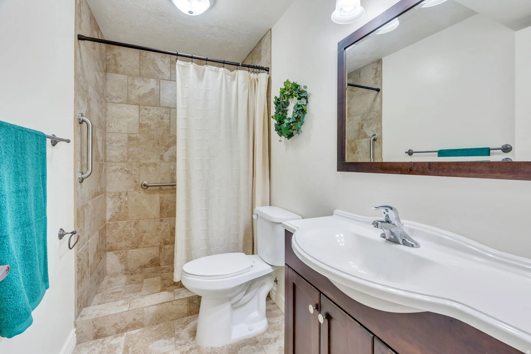 Walk-in shower with natural stone-look tile surround and grab bars