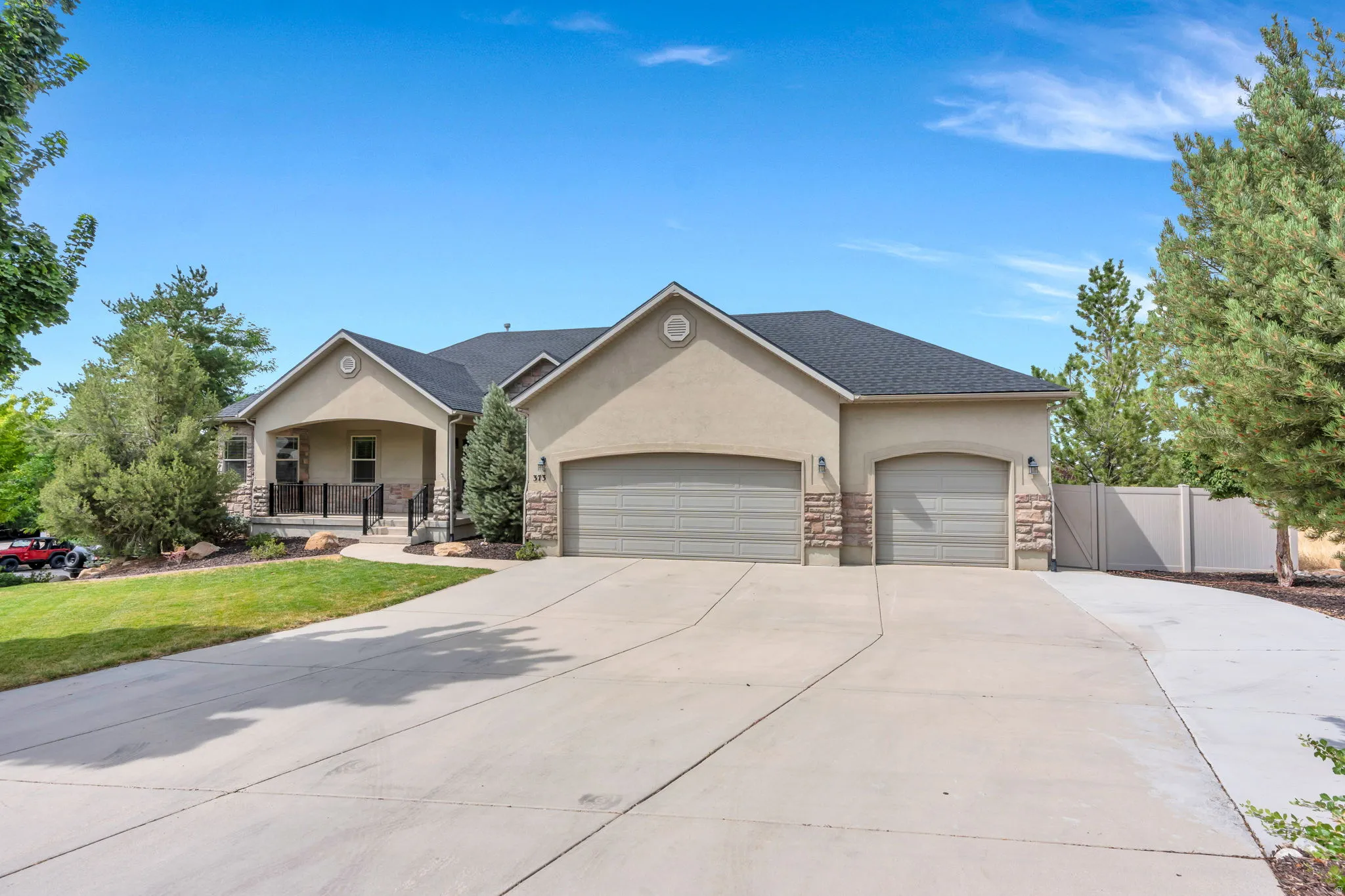 Stucco exterior with stone accents, a covered front porch, and a multi-car garage