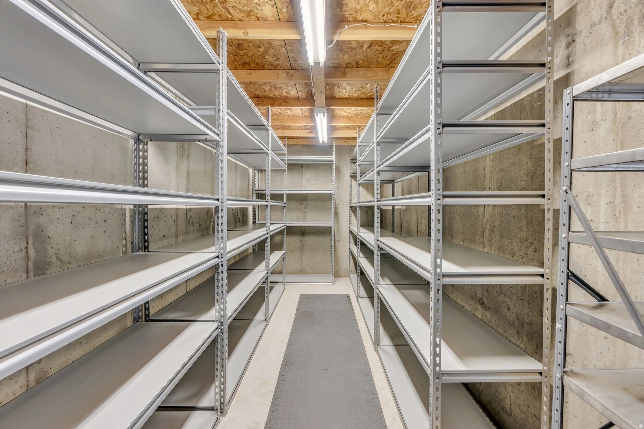 Built-in metal shelving units, concrete walls, concrete floor, overhead strip lighting, exposed wood ceiling