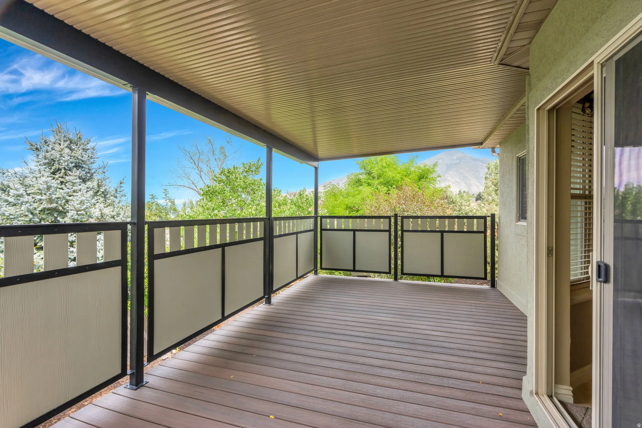 Covered outdoor deck with composite flooring, black metal railings, and privacy panels