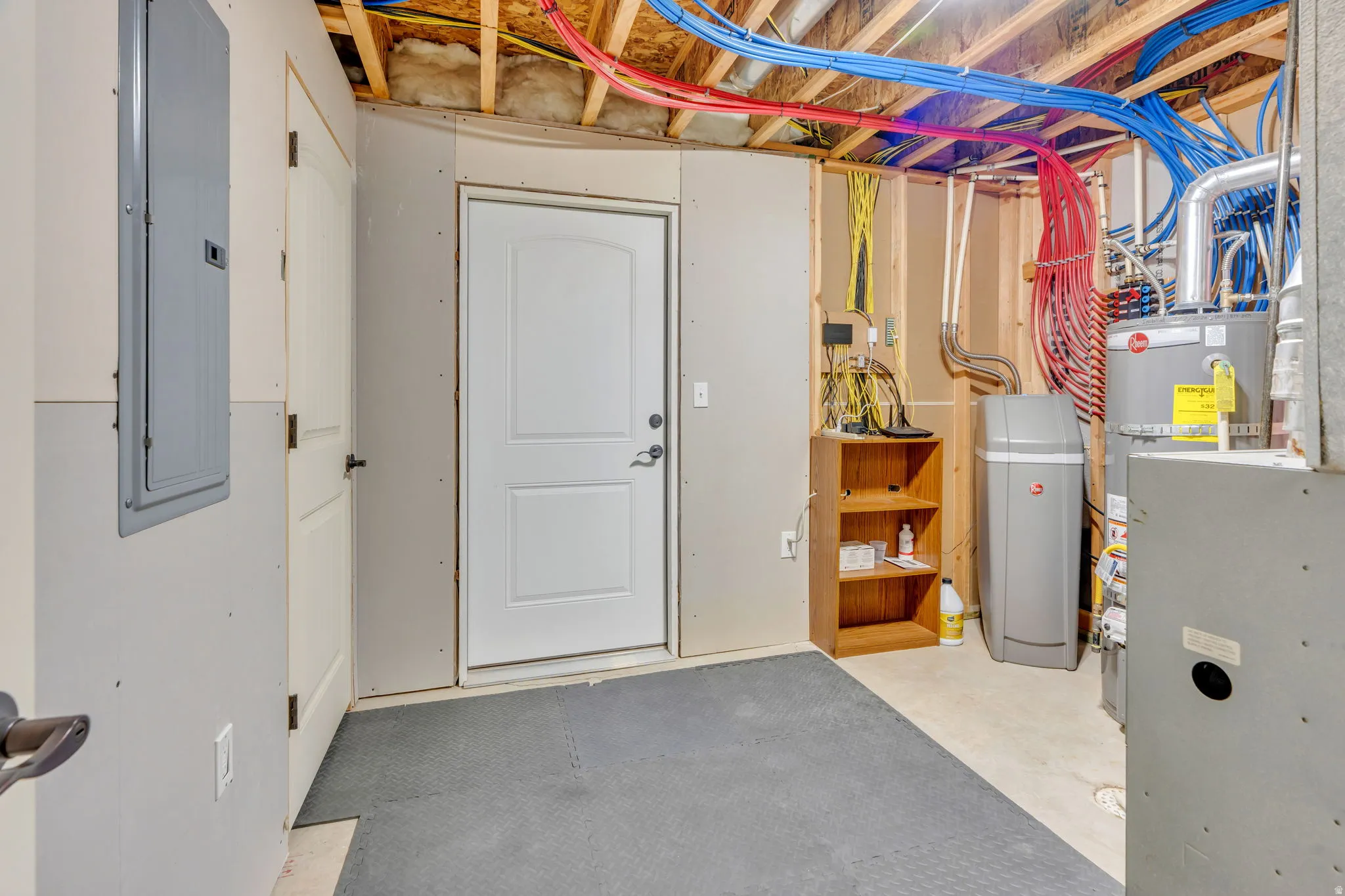 Utility space featuring exposed ceiling joists, a water heater, and a water softener system