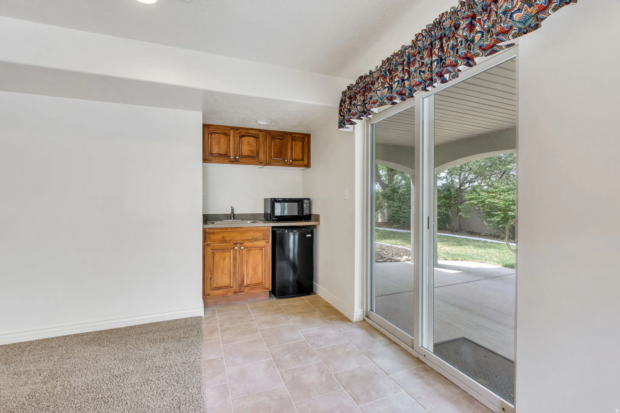 Compact kitchenette with wood cabinetry and stainless steel sink