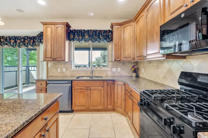 Kitchen with wood cabinetry, granite-style countertops, and a tile backsplash