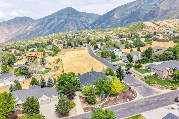 Mountainous backdrop, residential development, paved roads, natural landscaping, established trees