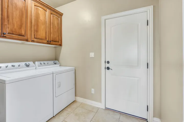 Laundry area featuring wood-finish cabinetry, tile flooring, and a paneled entry door