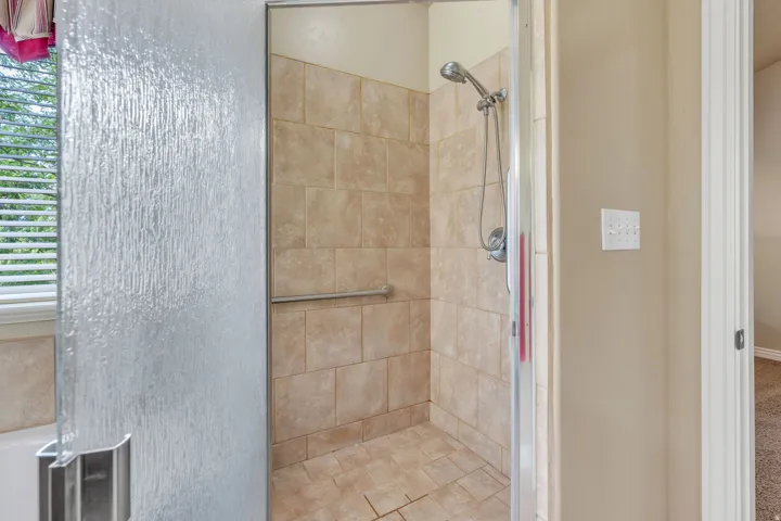 Walk-in shower with full-height tile surround, integrated grab bar, and hand-held shower fixture