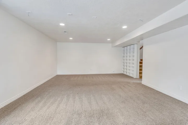 Spacious room featuring neutral carpeting, recessed lighting, and white painted walls