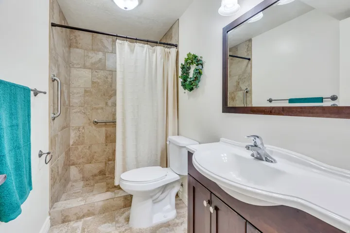 Walk-in shower with natural stone-look tile surround and grab bars