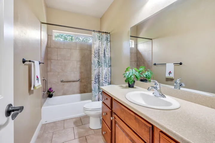 Bathroom featuring a built-in tub with tile surround, a single vanity with an integrated sink and base cabinetry, and a full-width wall mirror