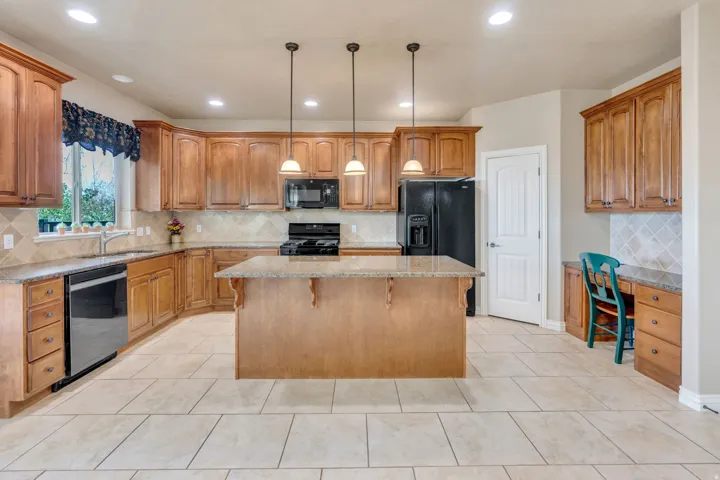 Kitchen featuring a central island, recessed lighting, tile flooring, wood cabinetry, and integrated desk area