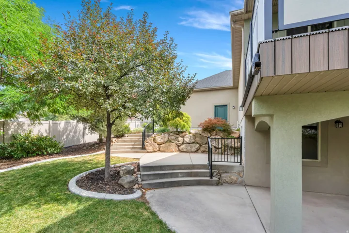 Terraced landscaping with concrete steps, wrought iron railing, and stone retaining wall