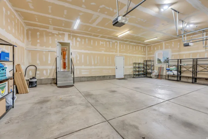 Spacious garage with concrete flooring, multiple overhead lighting fixtures, and direct interior access