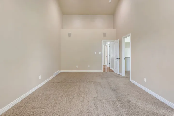 Vaulted ceilings, neutral carpet flooring, recessed lighting, and integrated wall speakers