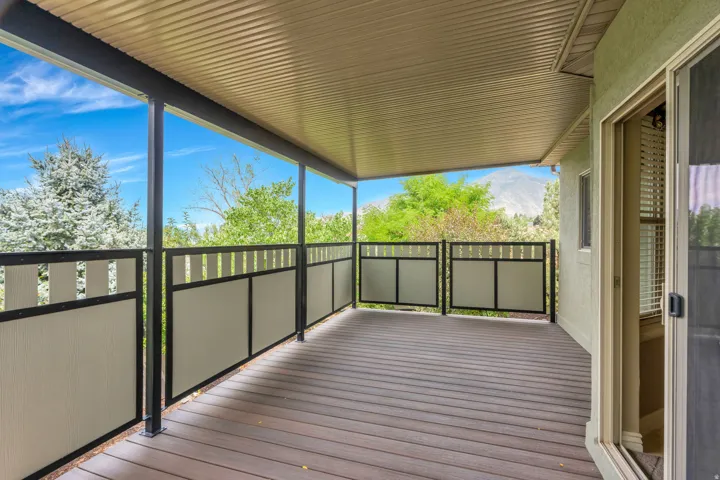 Covered outdoor deck with composite flooring, black metal railings, and privacy panels