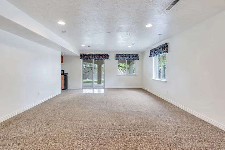 Spacious room featuring neutral carpet flooring, recessed lighting, and white walls