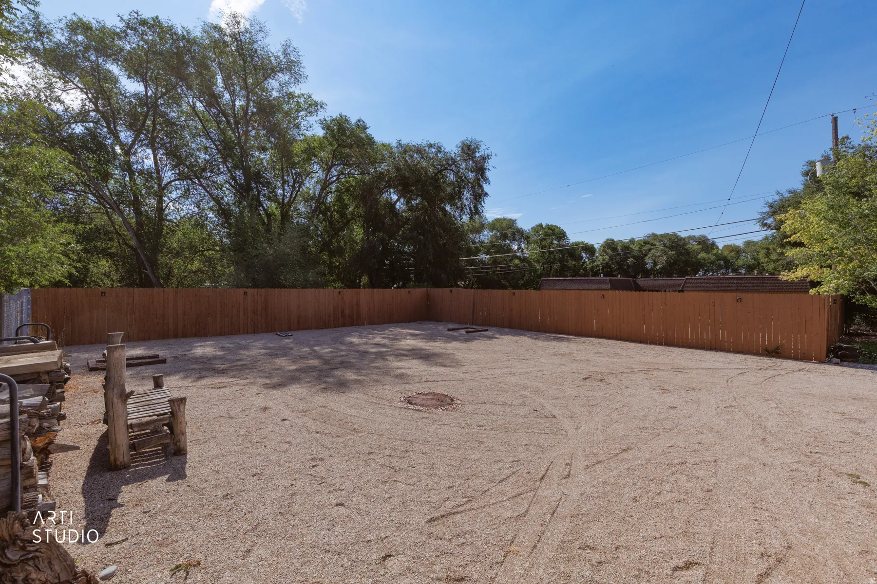 Spacious outdoor area with a gravel surface, enclosed by a tall wood privacy fence