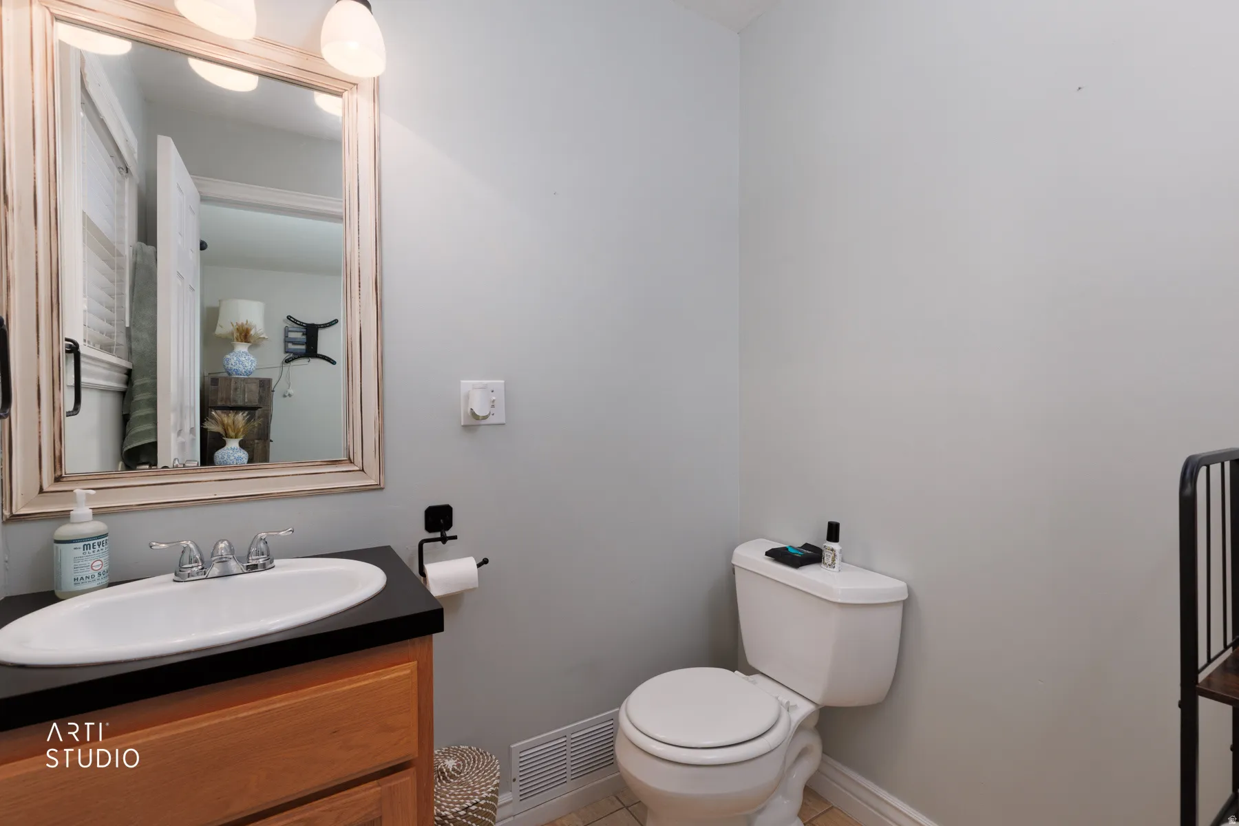 Bathroom vanity with a white oval sink, dark countertop, and wood-finish cabinetry