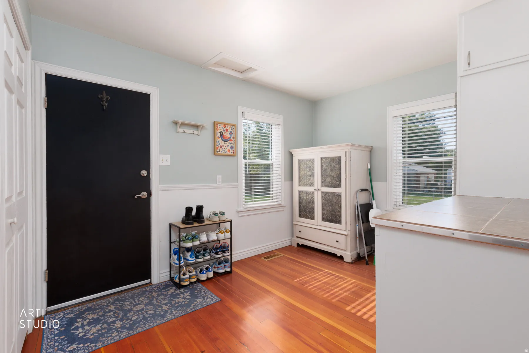Warm wood-finish flooring complements the light blue walls and crisp white wainscoting