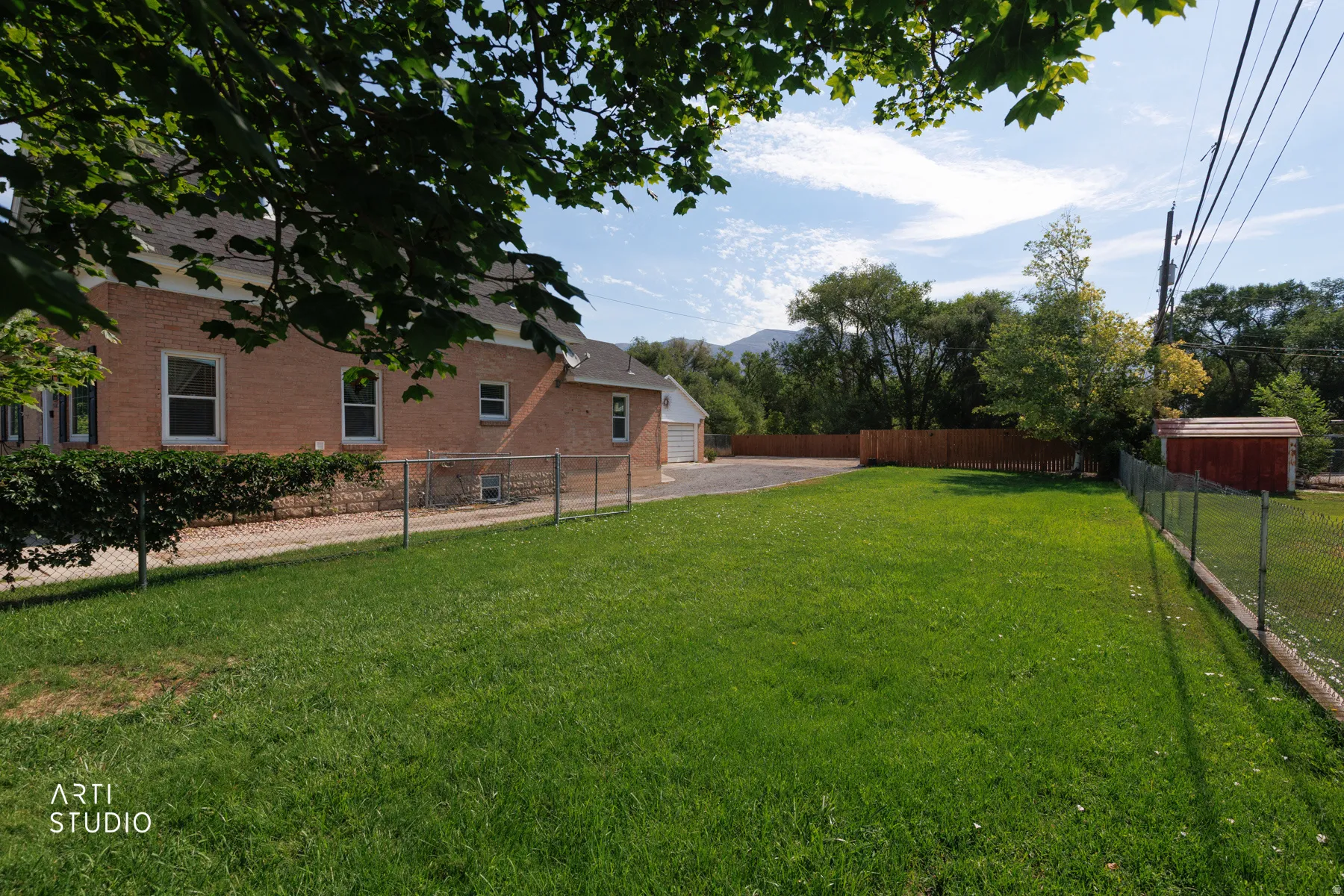 Expansive lawn area with a chain link fence and a red storage shed