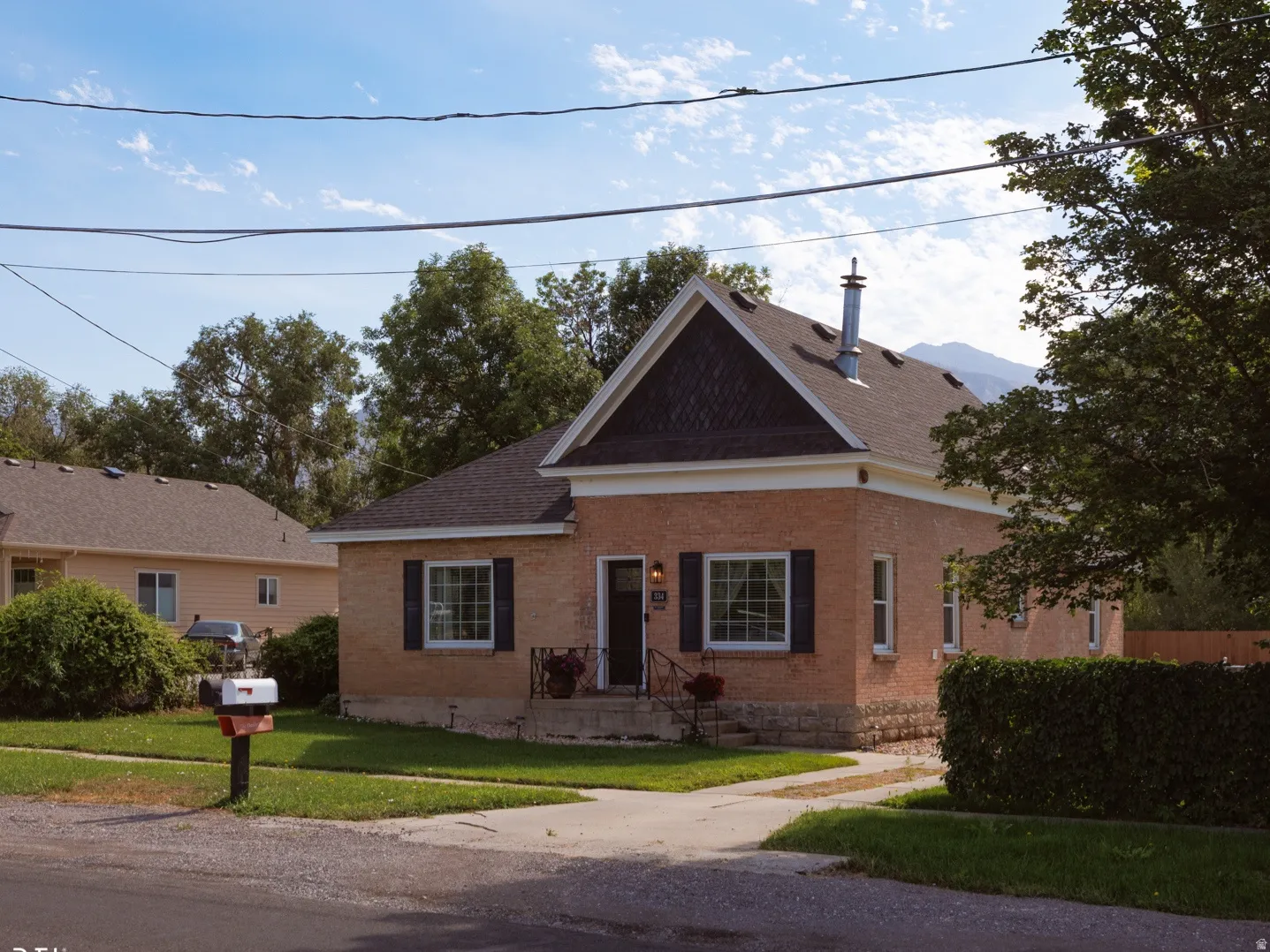 Brick exterior with a prominent front gable, dark shingle roofing, and black window shutters