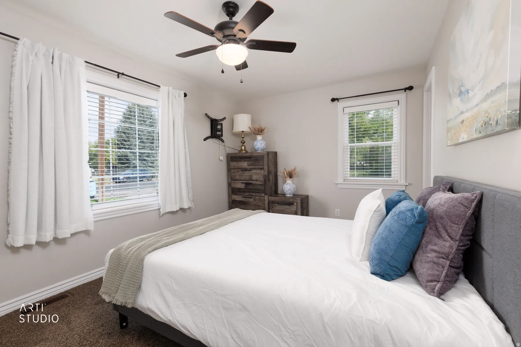 Bedroom featuring two windows with white blinds, neutral wall paint, and a ceiling fan with integrated lighting