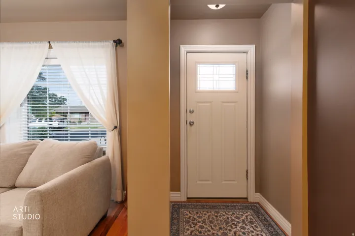 Entryway featuring a white door with decorative glass inserts, chrome hardware, and a ceiling-mounted light fixture