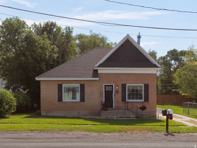 Brick exterior residence featuring a front gabled roofline and dark shingle roofing