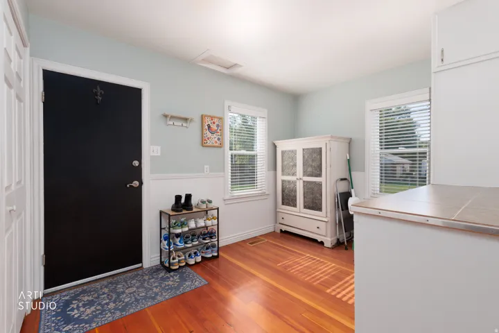 Warm wood-finish flooring complements the light blue walls and crisp white wainscoting