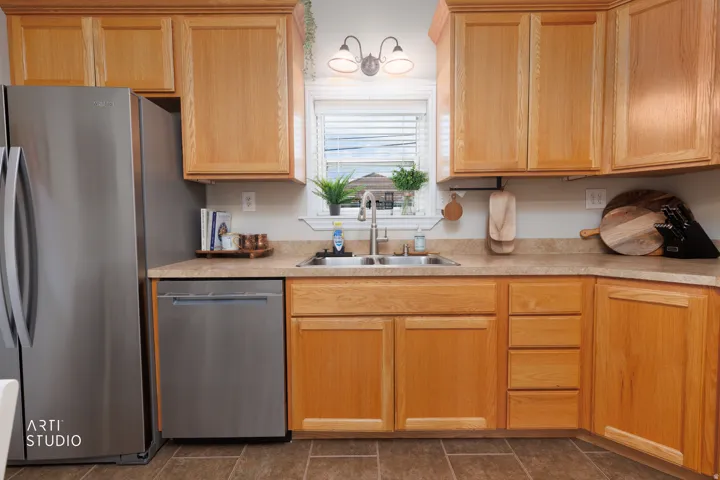 Kitchen featuring wood-finish cabinetry, stainless steel appliances, a double basin sink, and laminate countertops