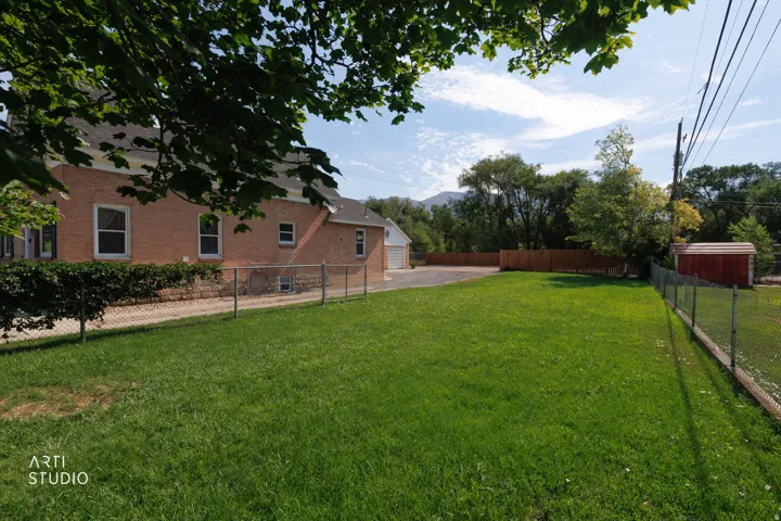 Expansive lawn area with a chain link fence and a red storage shed