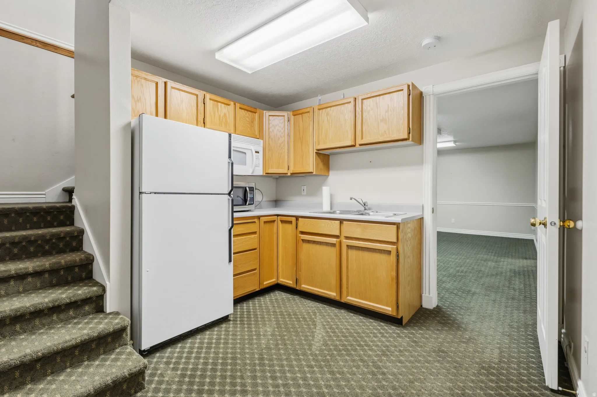 Compact kitchen area featuring wood cabinetry, laminate countertops, and a stainless steel sink