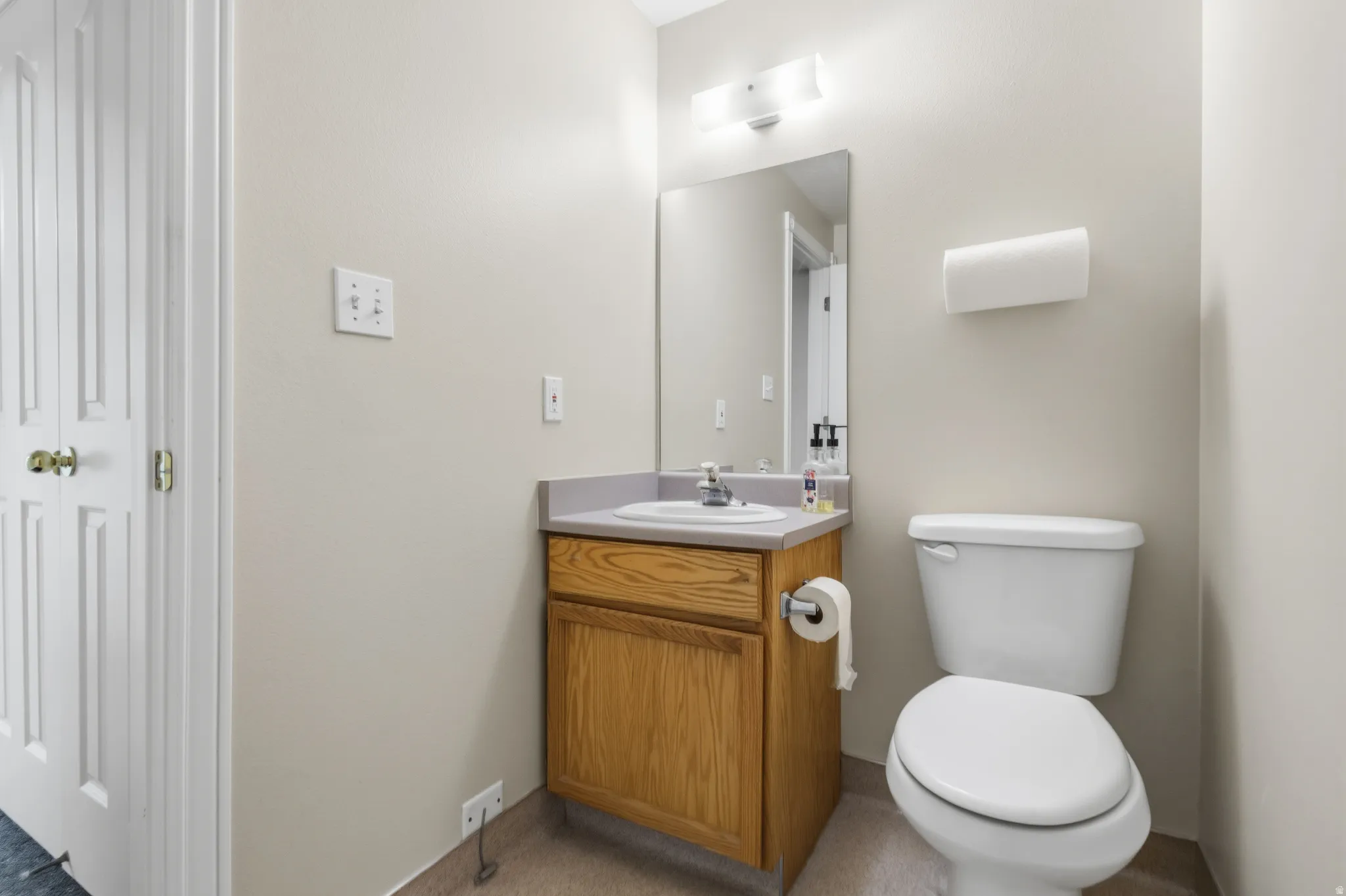 Vanity with a wood-finish cabinet, a light-colored countertop, and a white basin sink