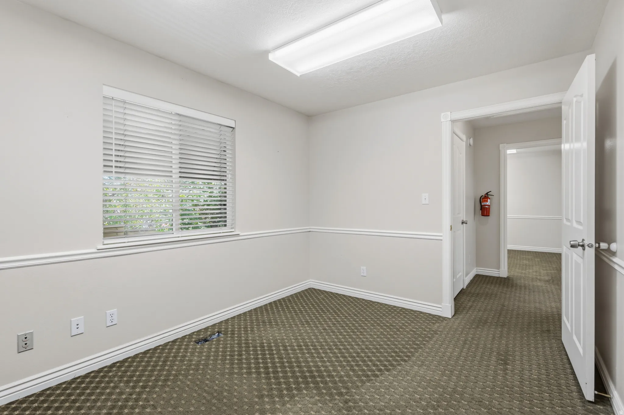 Interior room featuring patterned carpeting, neutral wall finishes, and white trim molding