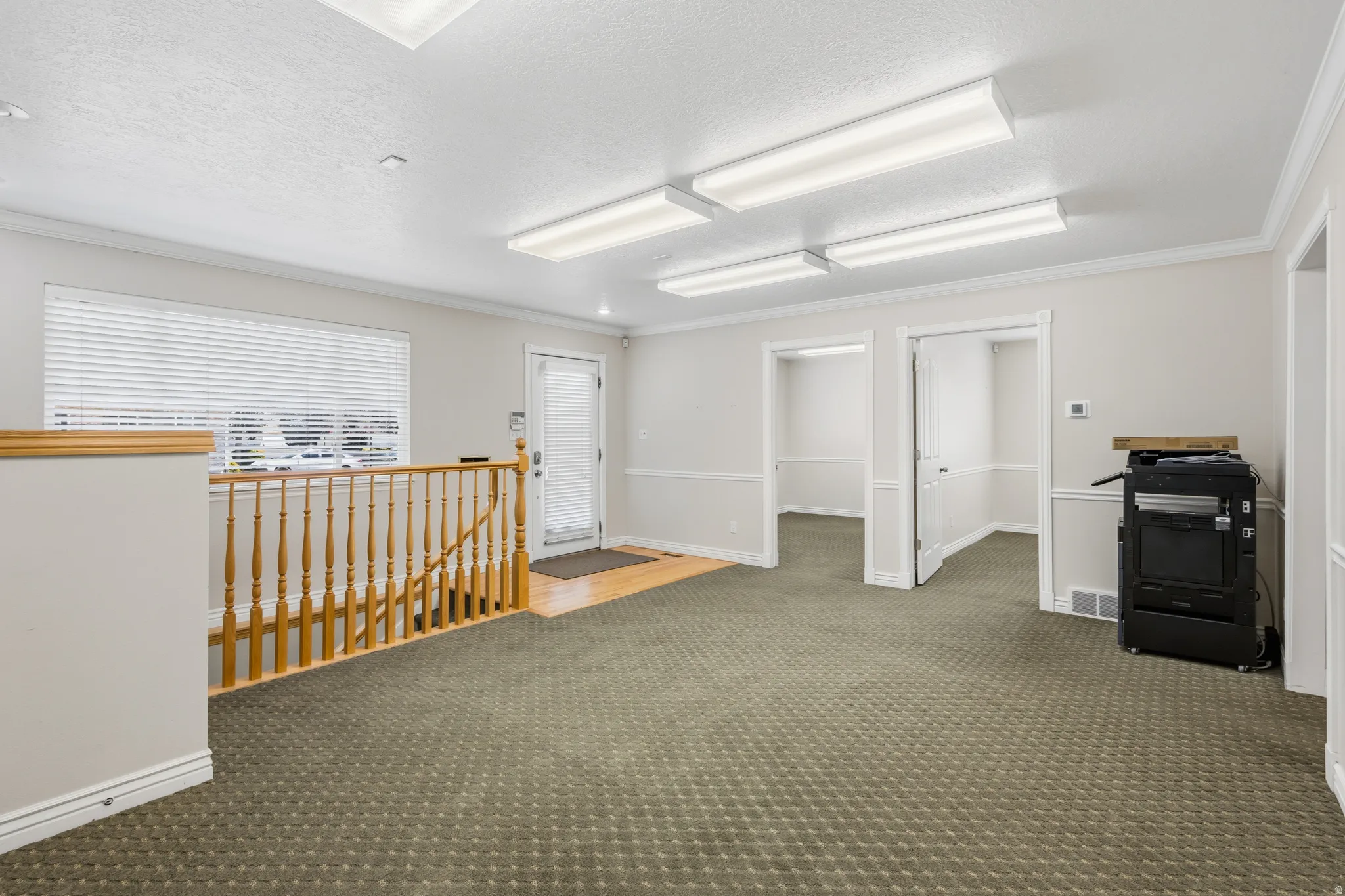 Interior space featuring patterned carpet flooring, neutral paint palette, and crown molding
