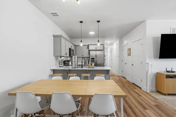 Kitchen with light gray cabinetry, stainless steel appliances, and a light-colored countertop island with pendant lighting