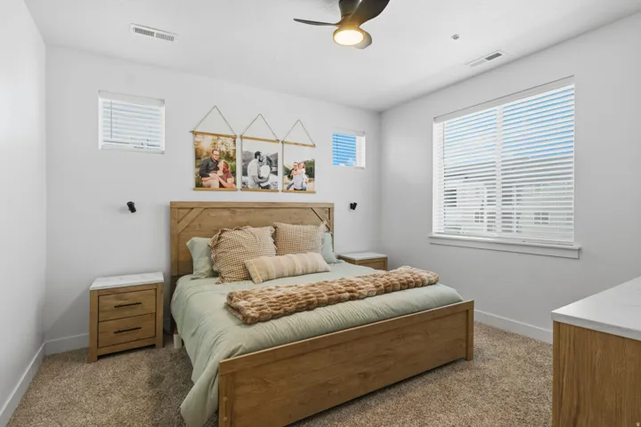 Carpeted room featuring a ceiling fan with integrated lighting, multiple windows with blinds, and white walls