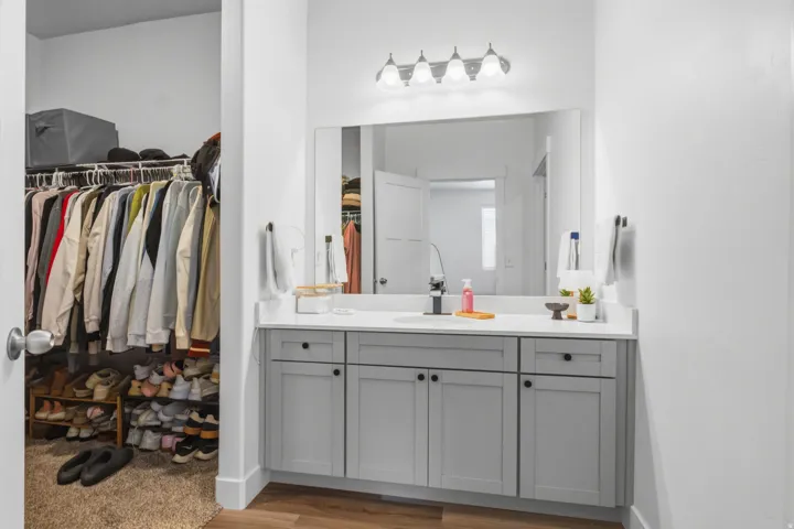 Bathroom vanity with light gray cabinetry, a white countertop, and a large mirror