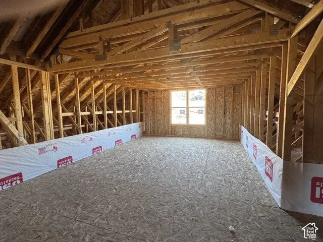 Unfinished interior space featuring exposed wood framing, high vaulted rafters, oriented strand board (OSB) flooring, and a single window installation