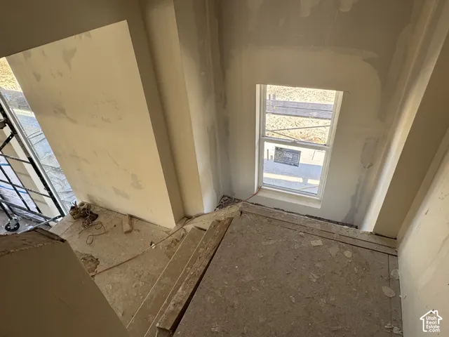 Stairwell featuring unfinished drywall walls and a single-hung window with white framing
