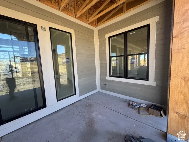 Covered patio with exposed structural timber framing, horizontal lap siding, and black-trimmed windows
