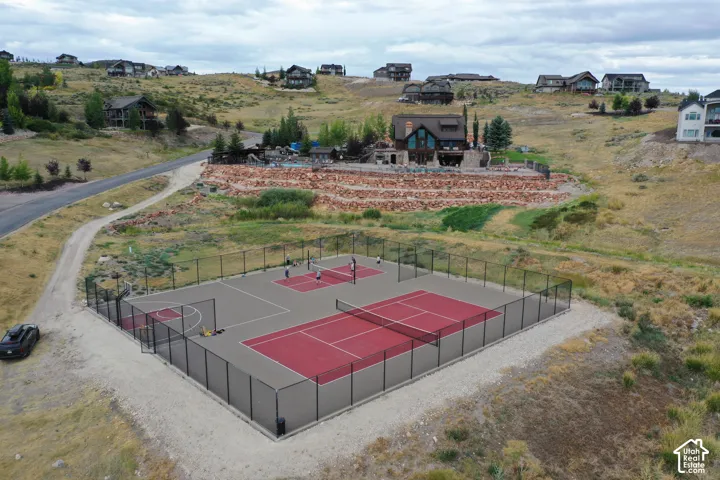 Multi-sport court featuring dedicated tennis and pickleball areas, a basketball hoop, and perimeter fencing