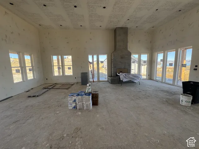 High-ceiling interior featuring a floor-to-ceiling textured masonry fireplace, numerous large-pane windows, and recessed lighting