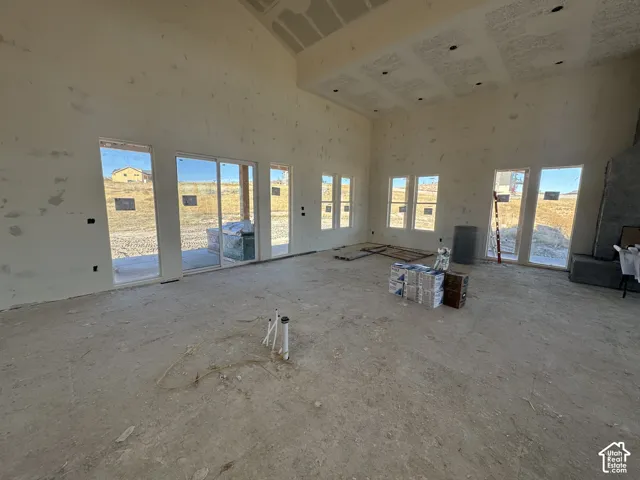 Vaulted ceiling, recessed lighting, expansive windows, glass sliding door, and stone-finished hearth