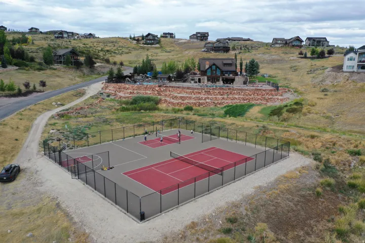 Multi-sport court featuring dedicated tennis and pickleball areas, a basketball hoop, and perimeter fencing