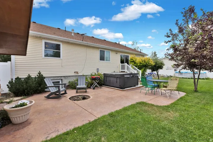 Expansive backyard featuring a stamped concrete patio, manicured lawn, mature trees, and privacy fencing