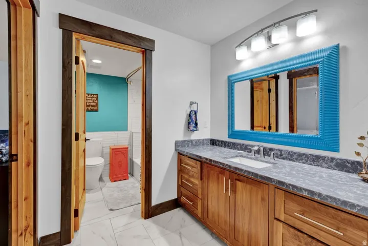 Bathroom vanity featuring wood cabinetry, a dark countertop, and an undermount sink with a chrome faucet