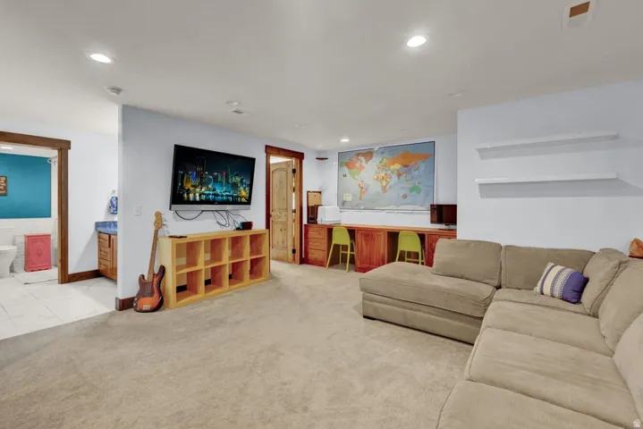 Spacious recreational room featuring recessed lighting, light-toned carpeting, and a built-in desk area with wood-finish cabinetry