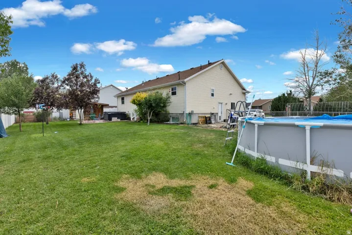 Expansive green lawn with mature trees and a white privacy fence