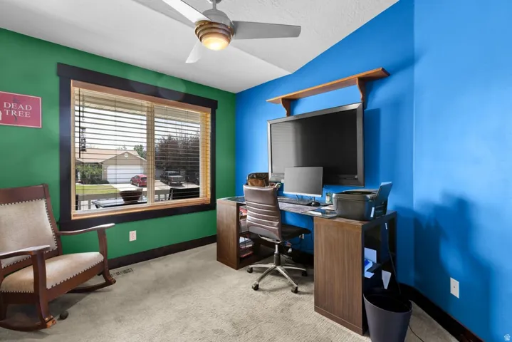 Room featuring a large window with horizontal blinds, a ceiling fan with integrated lighting, and carpet flooring